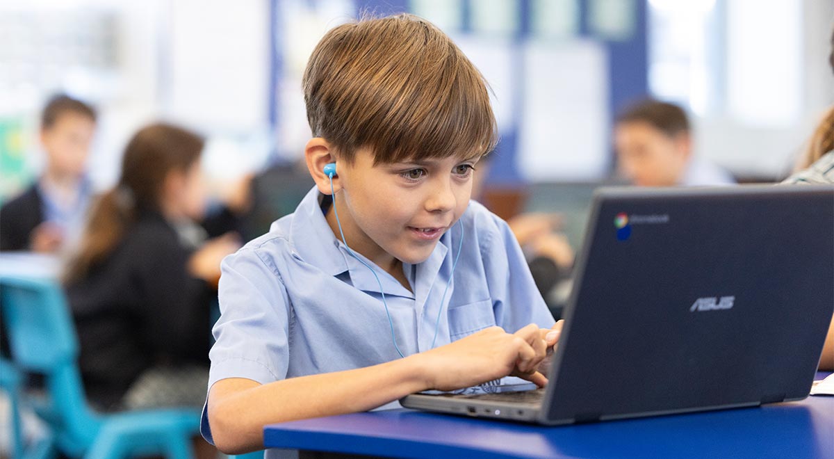 St Michael's Primary School, Baulkham hills student using Chromebook in class. He is wearing earbuds.