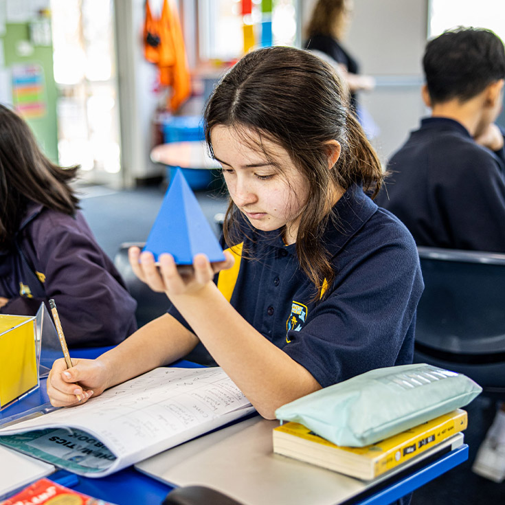 Student holding a triangular prism at St Mary's Primary School Rydalmere