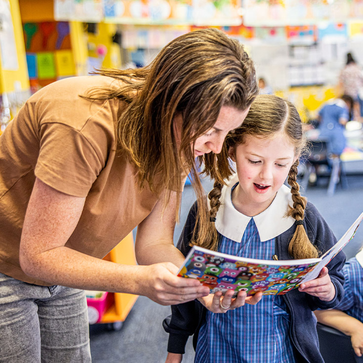 Teacher reading with her student in the classroom at St Mary's Primary School Rydalmere