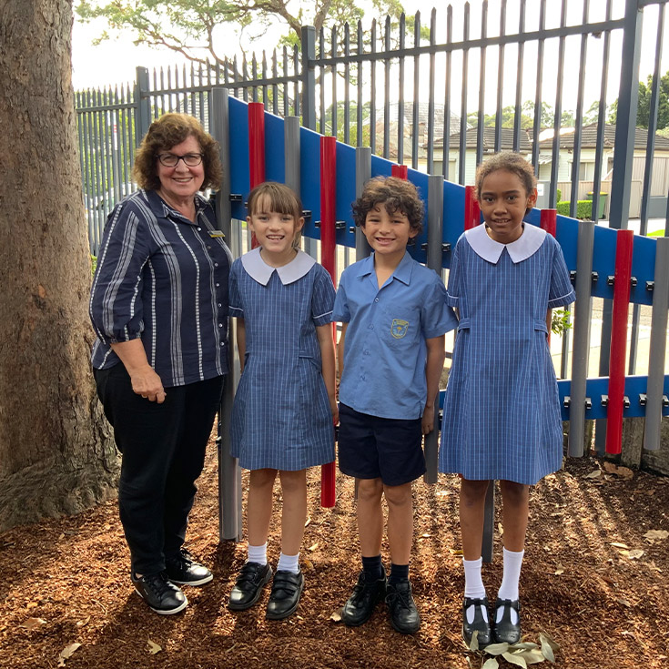 Defence School Mentor Dianne Woods with students in the playground at St Mary's Primary School Rydalmere