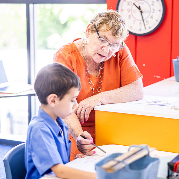 Teacher helping her student read in the classroom at St Mary's Primary School Rydalmere