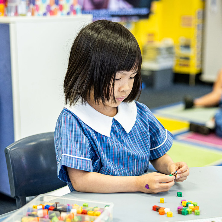 Student playing with beads in the classroom at St Mary's Primary School Rydalmere